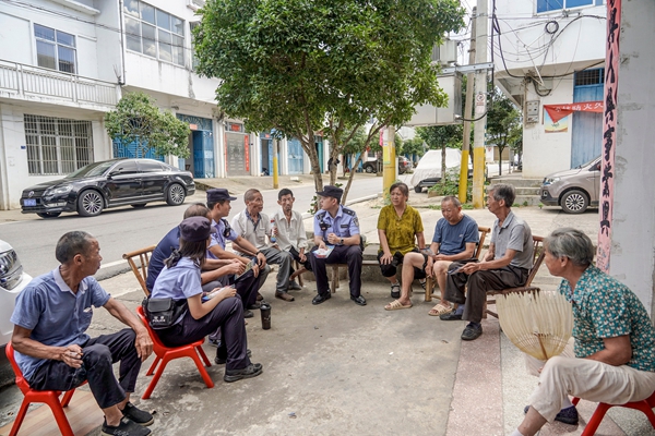 社区民警向聚集在大树底下纳凉的村民宣传防电诈知识.jpg
